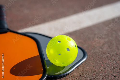 pickleball game, colorful orange and grey pickleball paddle with yellow ball , outdoor sport leisure activity.