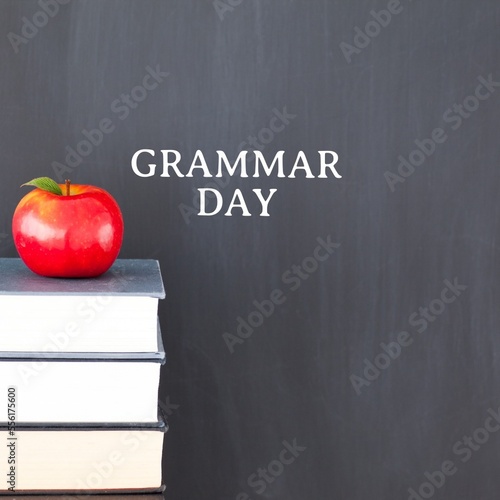 Fototapeta Naklejka Na Ścianę i Meble -  Apple on stack of books against grammar day text banner on grey background