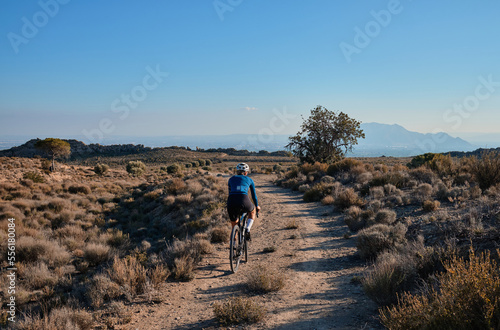 Foto woman cyclist riding a gravel bicycle on the road in hills with mountain view, A