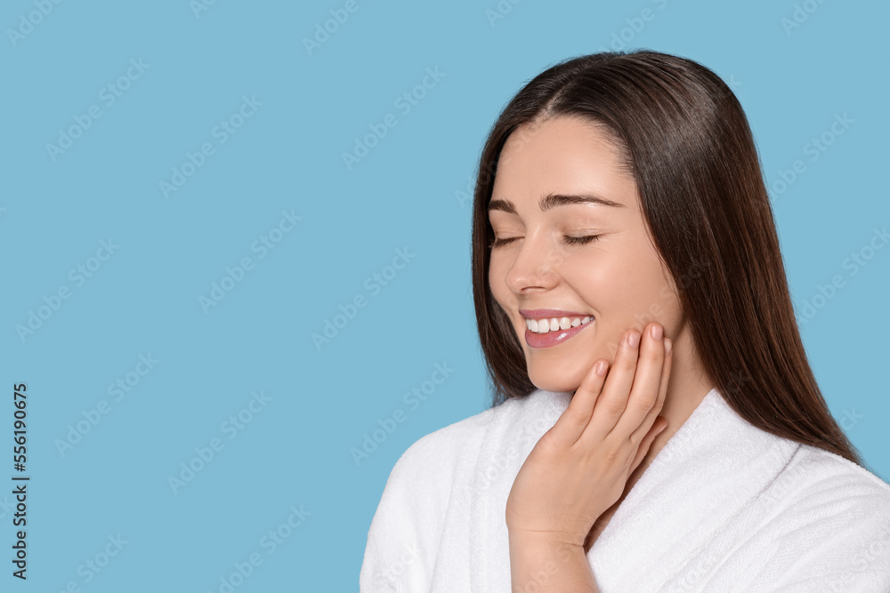 Portrait of attractive young woman in bathrobe on light blue background, space for text. Spa treatment Portrait of attractive young woman in bathrobe on light blue background, space for text. Spa treatment