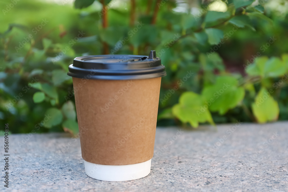 Disposable paper cup with plastic lid on stone parapet outdoors, space for text Disposable paper cup with plastic lid on stone parapet outdoors, space for text
