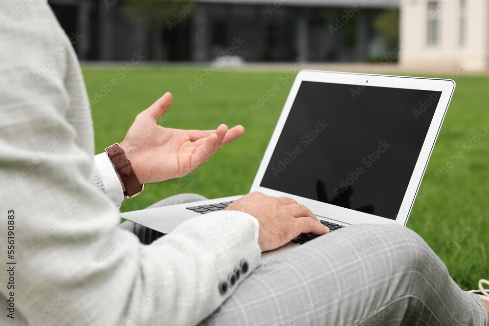 Businessman with laptop on green grass outdoors, closeup Businessman with laptop on green grass outdoors, closeup