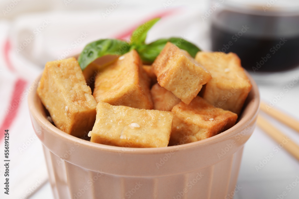 Delicious fried tofu with basil and sesame seeds in bowl on table, closeup Delicious fried tofu with basil and sesame seeds in bowl on table, closeup