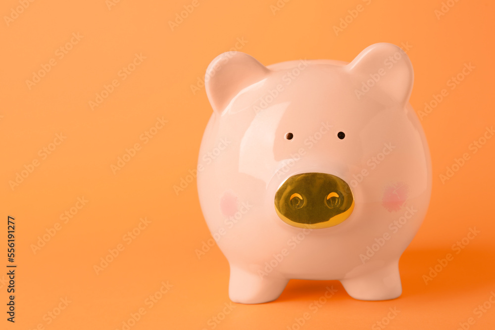 Ceramic piggy bank on orange background. Space for text Ceramic piggy bank on orange background. Space for text