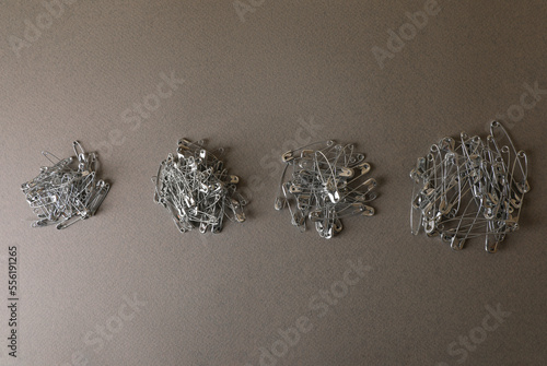 Piles of safety pins on grey textured background, flat lay