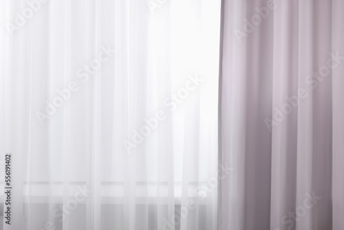 Light grey window curtains and white tulle indoors, closeup © New Africa