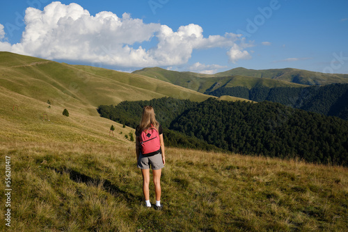 The girl stands on the edge of a high mountain . The girl looks at the beautiful mountain landscape