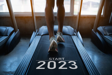 Happy new year 2023,2023 symbolizes the start of the new year. Close up of feet, sportman runner running on treadmill in fitness club. Cardio workout. Healthy lifestyle, guy training in gym.