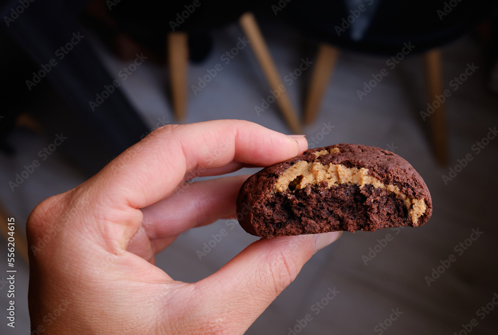 Woman's hand showing a fluffy thick chocolate brownie cookie cut in half with peanut Woman's hand showing a fluffy thick chocolate brownie cookie cut in half with peanut