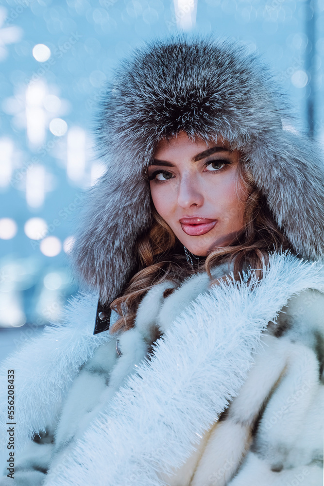 Outdoor close up portrait of young beautiful happy smiling girl with red lips, wearing in a fur coatand a fur hat, posing in street. Winter fashion, Christmas holidays concept. Copy space Outdoor close up portrait of young beautiful happy smiling girl with red lips, wearing in a fur coatand a fur hat, posing in street. Winter fashion, Christmas holidays concept. Copy space