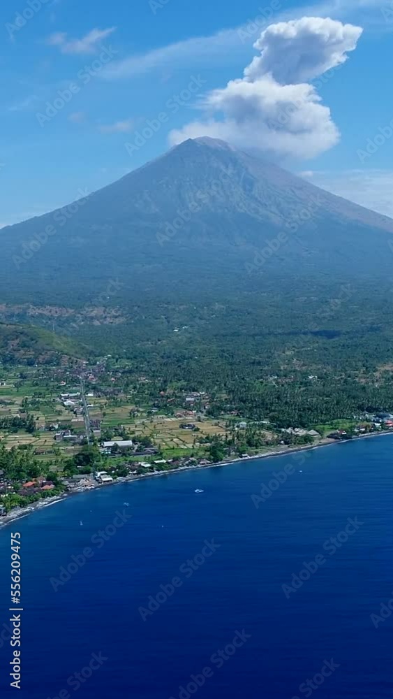 Vertical video of Coast of island with black sand beach and volcano erupting in background Vertical video of Coast of island with black sand beach and volcano erupting in background