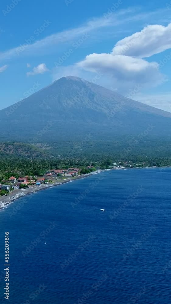 Vertical video of Coast of island with black sand beach and volcano erupting in background Vertical video of Coast of island with black sand beach and volcano erupting in background