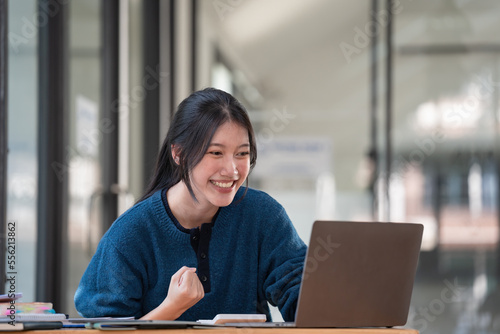Stampa su tela Young Asian women celebrate success or happy poses with a laptop.