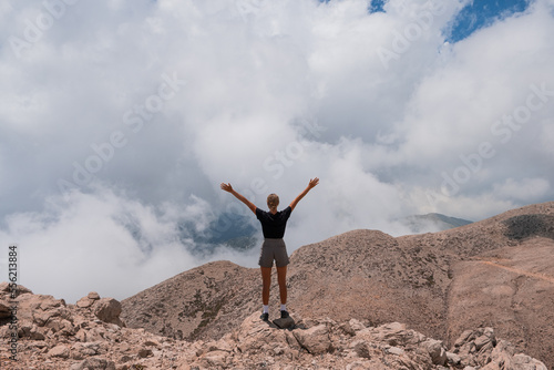 The girl stands on the edge of a high mountain in the clouds. The girl looks at the beautiful mountain landscape Antalya Turkey