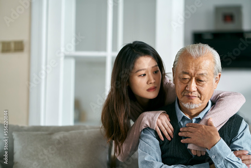 Fototapeta young asian adult daughter conforting senior father at home