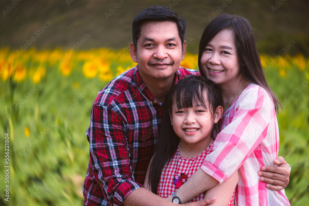 Happy family with parents and daughter, smiling together in sunflower field.Concept of lovely family and travel Happy family with parents and daughter, smiling together in sunflower field.Concept of lovely family and travel