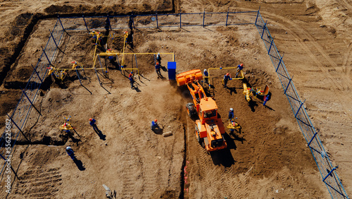 Aerial view excavator and construction workers working on construction site in open field. Pipe laying in trench for gasification. Top point of shooting. Repair and restoration of natural gas supply..
