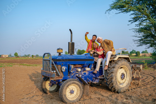 Indian farmers sitting on tractor at agriculture field.