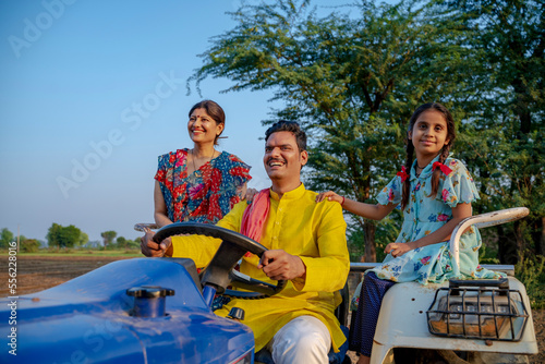 Indian farmer sitting on tractor with wife and little daughter. Indian rural family.