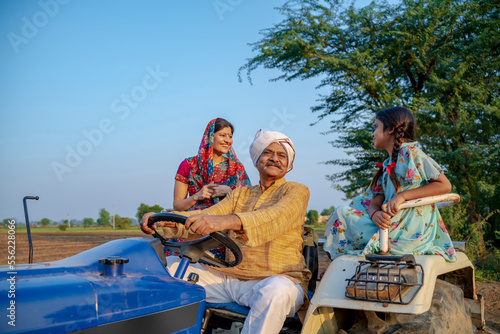 Indian senior farmer sitting on tractor with family. Indian rural family. © Niks Ads