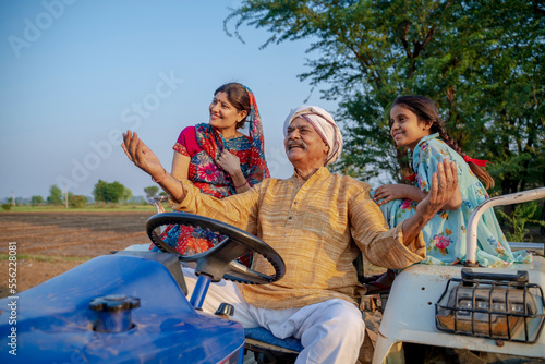 Indian senior farmer sitting on tractor with family. Indian rural family.