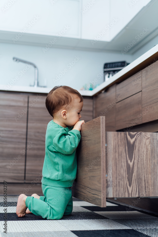 Little baby playing in kitchen. Baby alone in the kitchen. Child in danger Little baby playing in kitchen. Baby alone in the kitchen. Child in danger