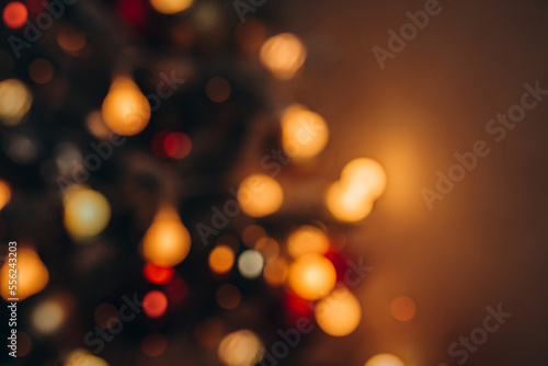 Blurred and soft focused warm golden lights of Christmas tree blurred bokeh on dark background. 