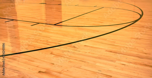 Interior of empty modern basketball indoor sport court, semigloss coating wooden floor, artificial lights reflected