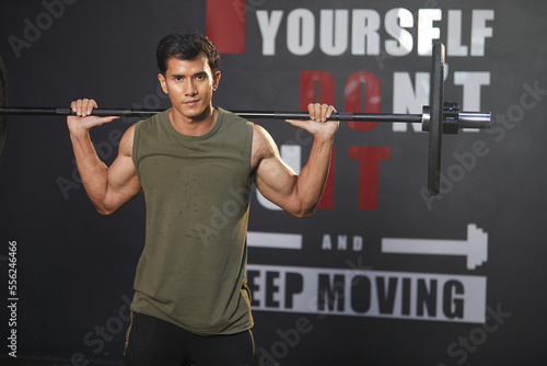 young athletic man exercising with barbell in the gym