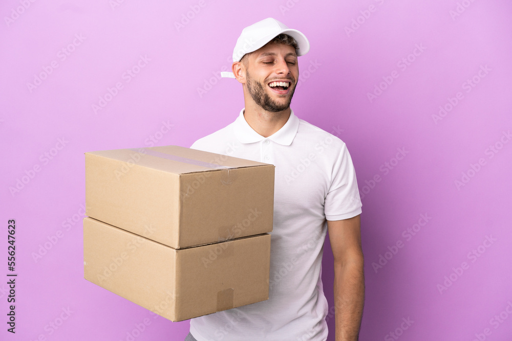 Delivery caucasian man isolated on purple background laughing Delivery caucasian man isolated on purple background laughing