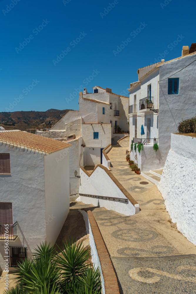 Fototapeta premium Cobblestone streets forming patterns on the ground and white houses in the village of Frigiliana in Malaga province, Andalucia, Spain.