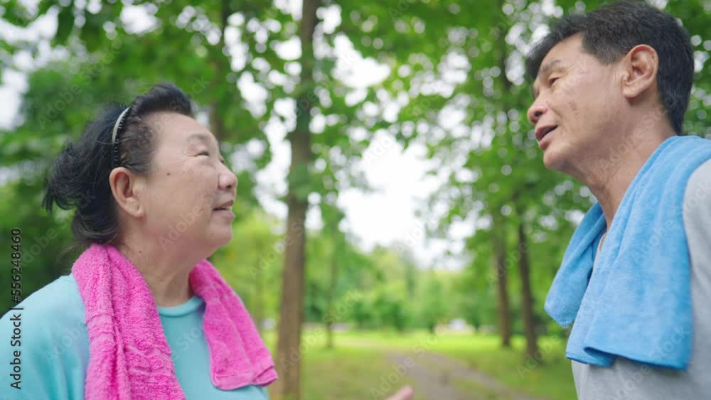 Asian cheerful happy retirement aged people talking while resting after jogging inside the green recreational park. Concept of health care for old age, Elderly love care for each other healthy outdoor Asian cheerful happy retirement aged people talking while resting after jogging inside the green recreational park. Concept of health care for old age, Elderly love care for each other healthy outdoor