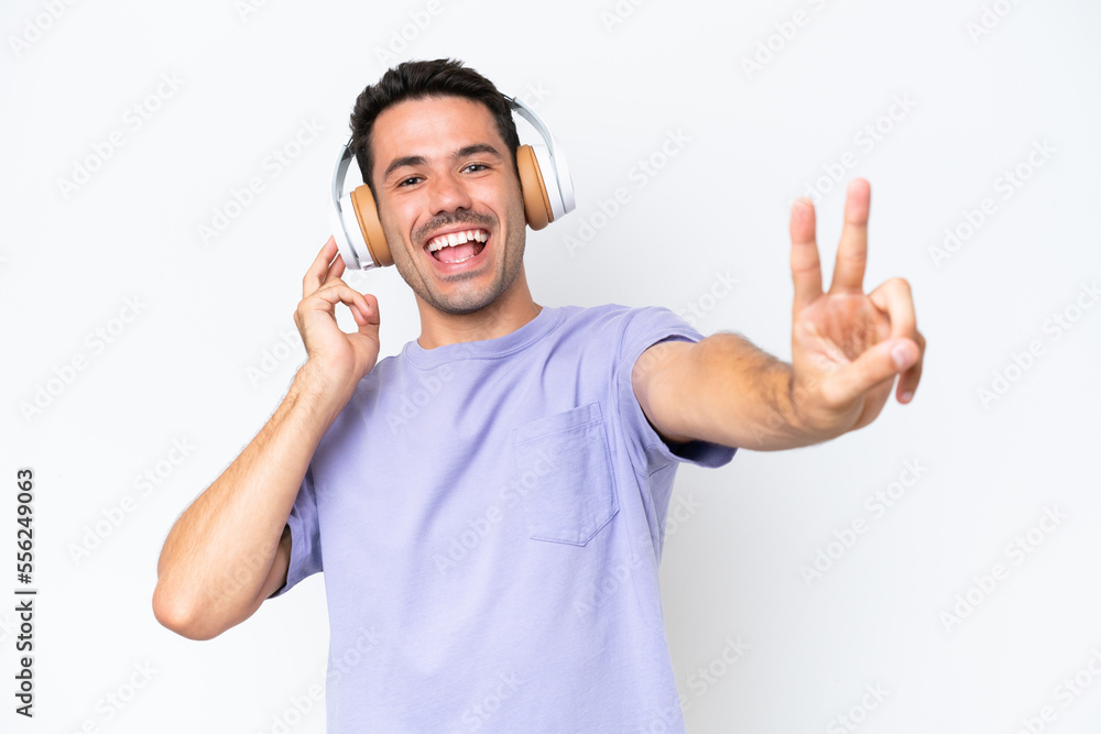Fototapeta premium Young handsome man over isolated white background listening music and singing