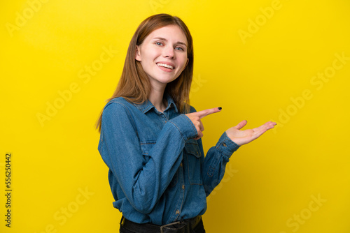 Young English woman isolated on yellow background holding copyspace imaginary on the palm to insert an ad