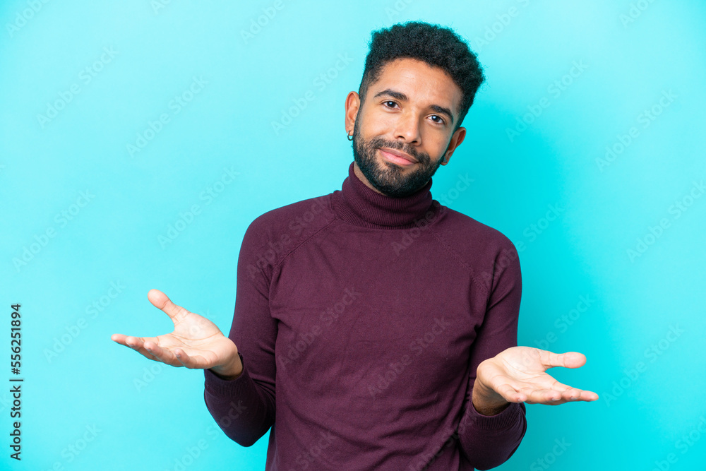 Young Brazilian man isolated on blue background having doubts Young Brazilian man isolated on blue background having doubts