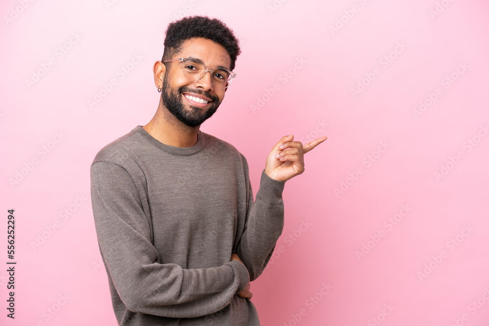 Young Brazilian man isolated on pink background pointing finger to the side Young Brazilian man isolated on pink background pointing finger to the side