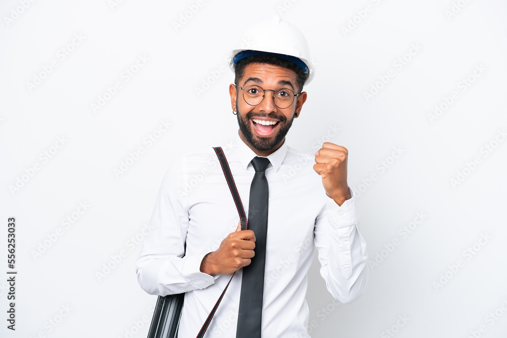 Young architect Brazilian man with helmet and holding blueprints isolated on white background celebrating a victory in winner position Young architect Brazilian man with helmet and holding blueprints isolated on white background celebrating a victory in winner position