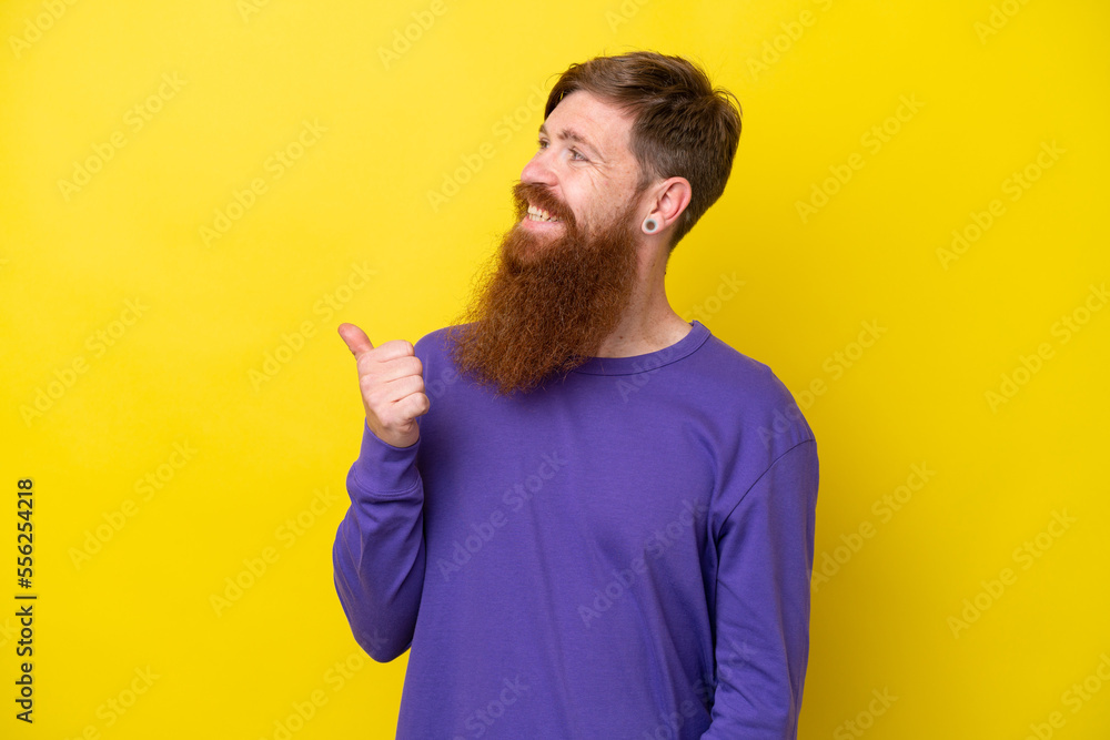 Redhead man with beard isolated on yellow background pointing to the side to present a product Redhead man with beard isolated on yellow background pointing to the side to present a product