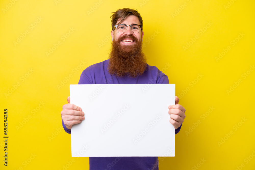 Redhead man with beard isolated on yellow background holding an empty placard with happy expression Redhead man with beard isolated on yellow background holding an empty placard with happy expression