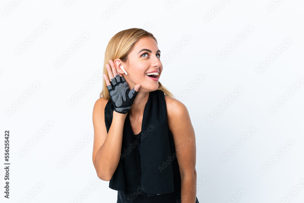 Blonde Uruguayan sport girl isolated on white background listening to something by putting hand on the ear Blonde Uruguayan sport girl isolated on white background listening to something by putting hand on the ear