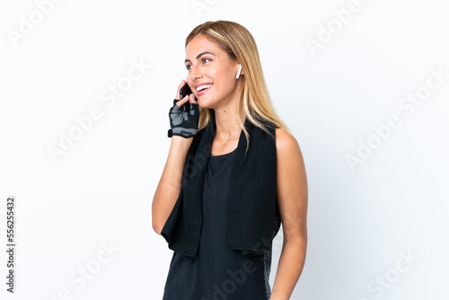 Blonde Uruguayan sport girl isolated on white background keeping a conversation with the mobile phone