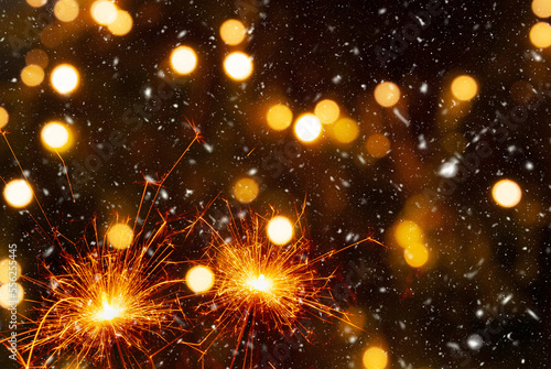 Burning sparklers on abstract snowy background, party concept