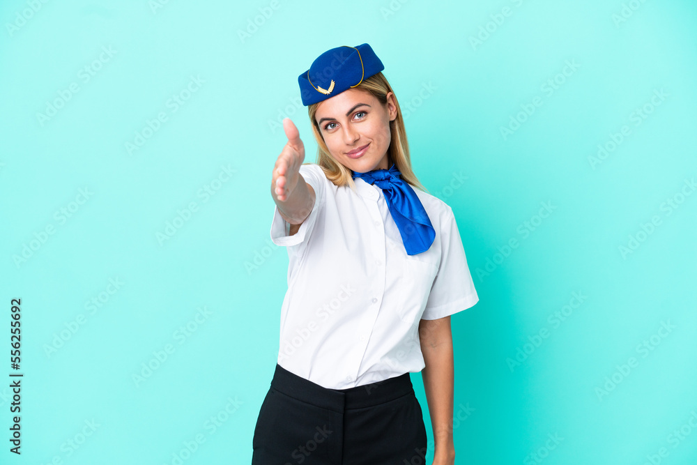 Airplane stewardess Uruguayan woman isolated on blue background shaking hands for closing a good deal Airplane stewardess Uruguayan woman isolated on blue background shaking hands for closing a good deal