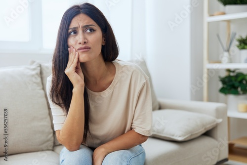 Woman toothache, tooth root inflammation sitting on sofa at home © SHOTPRIME STUDIO