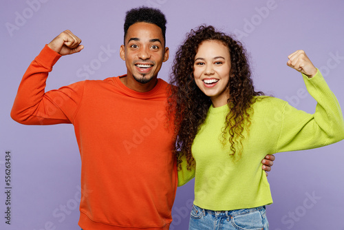 Young couple two friend family man woman of African American ethnicity in casual clothes together show hand biceps muscles demonstrate strength power isolated on pastel plain light purple background
