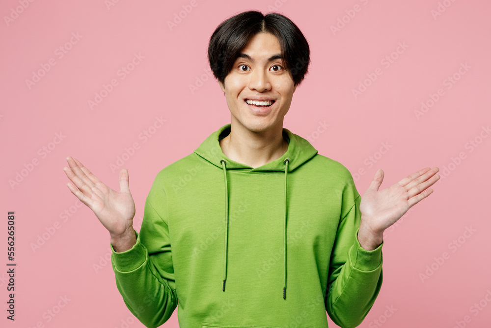 Young overjoyed excited happy exultant man of Asian ethnicity wear green hoody look camera spread hands say wow isolated on plain pastel light pink background studio portrait People lifestyle concept Young overjoyed excited happy exultant man of Asian ethnicity wear green hoody look camera spread hands say wow isolated on plain pastel light pink background studio portrait People lifestyle concept