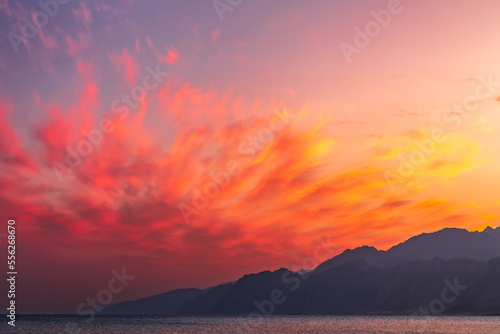 Picturesque sunset landscape on beach with coloful clouds and mountains in background, Dahab, Egypt