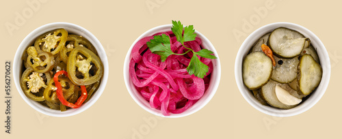 A pattern of pickled jalapeno peppers, red onions and cucumbers in white bowls on yellow background. Traditional meat snacks. Healthy fermented food.
