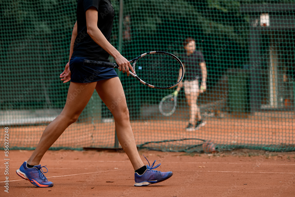 view on beautiful athletic legs of walking female tennis player with racket in her hand