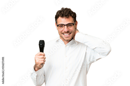 Brazilian man picking up a microphone over isolated chroma key background laughing